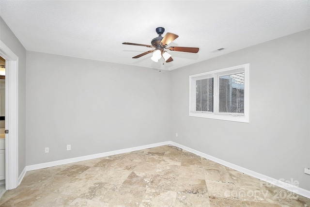 unfurnished room featuring ceiling fan, a textured ceiling, baseboards, visible vents, and stone tile flooring