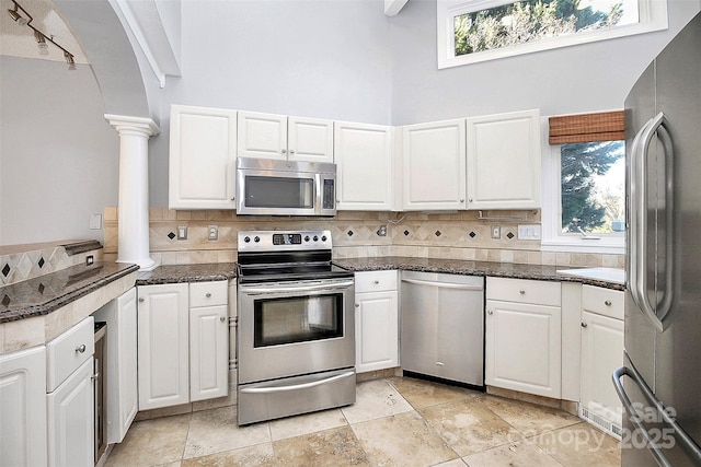 kitchen with ornate columns, decorative backsplash, white cabinetry, and stainless steel appliances