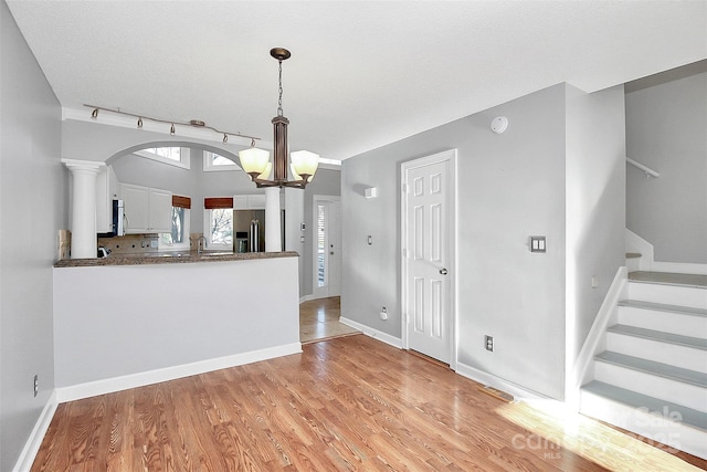 kitchen with light wood-type flooring, white cabinets, dark countertops, and stainless steel appliances