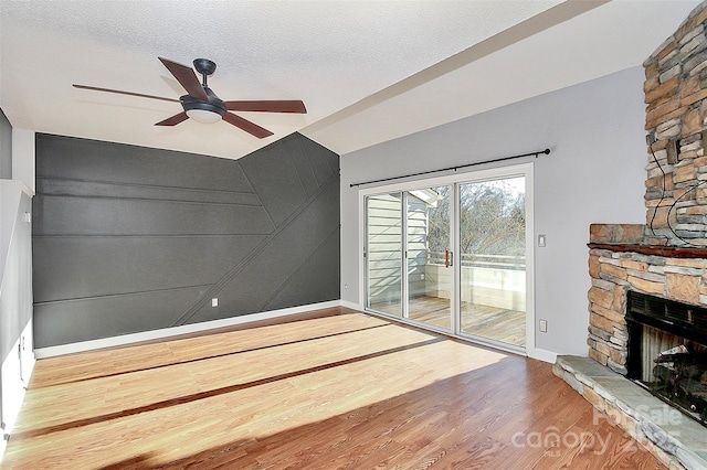 unfurnished living room featuring baseboards, a fireplace, a ceiling fan, and wood finished floors