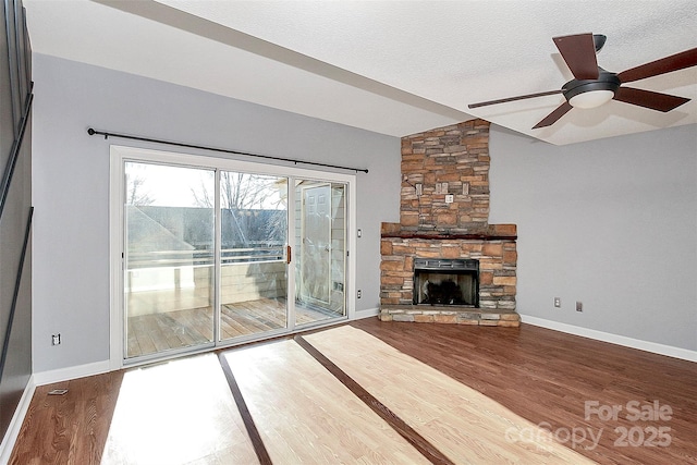 unfurnished living room with wood finished floors, lofted ceiling, a fireplace, baseboards, and ceiling fan
