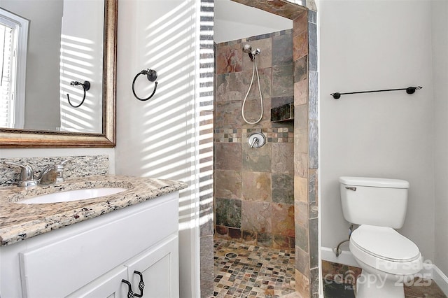 bathroom featuring vanity, baseboards, walk in shower, and toilet