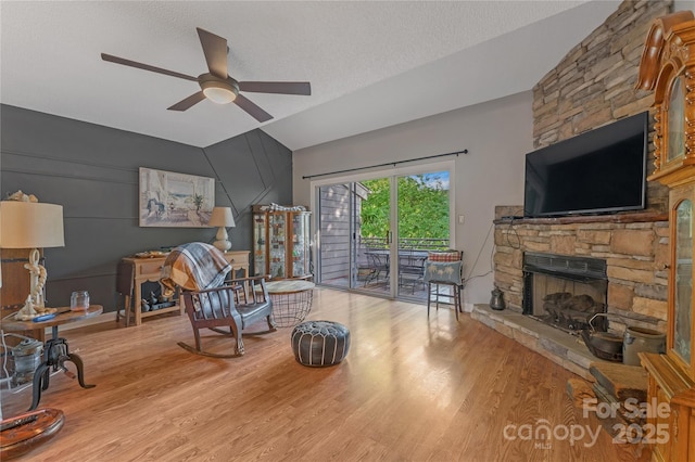 13932 Queens Harbor Rd, Charlotte, NC 28278 - living area featuring vaulted ceiling, a ceiling fan, a stone fireplace, wood finished floors, and a textured ceiling
