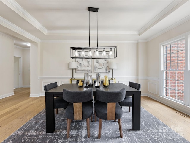 dining space featuring visible vents, ornamental molding, and wood finished floors