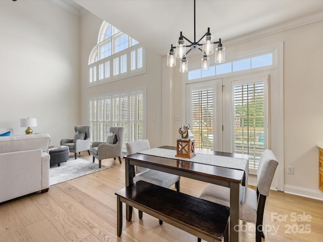 dining space with plenty of natural light, ornamental molding, light wood finished floors, and a chandelier