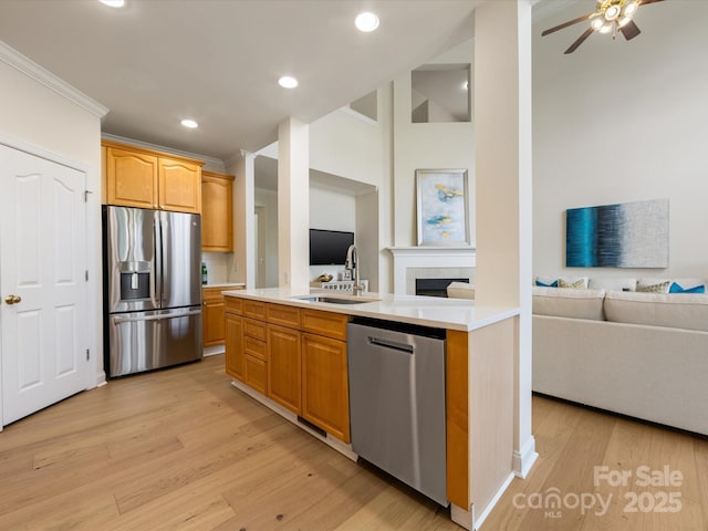 kitchen featuring appliances with stainless steel finishes, light countertops, open floor plan, light wood-style floors, and ornamental molding