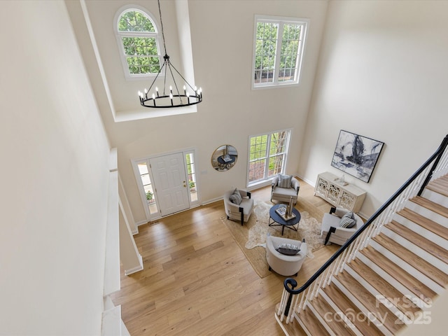 foyer featuring stairs, a chandelier, a healthy amount of sunlight, and light wood-style flooring