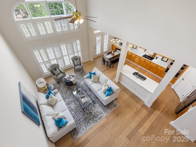 living area featuring a high ceiling, ceiling fan, a wealth of natural light, and wood finished floors