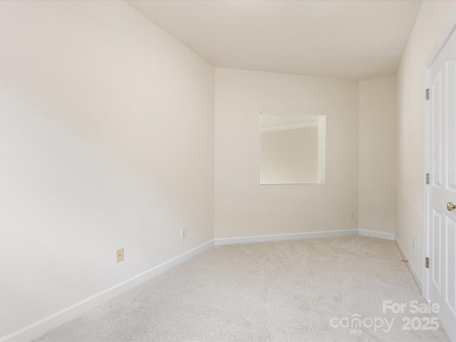 spare room with baseboards and light colored carpet