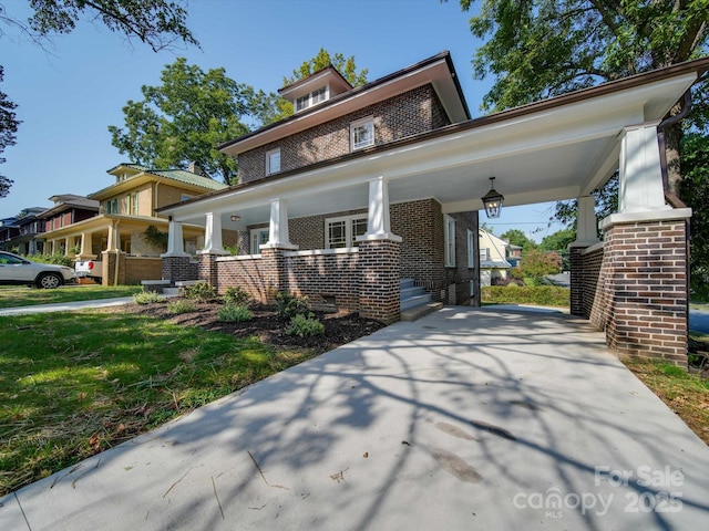 view of front of property with covered porch, concrete driveway, and brick siding