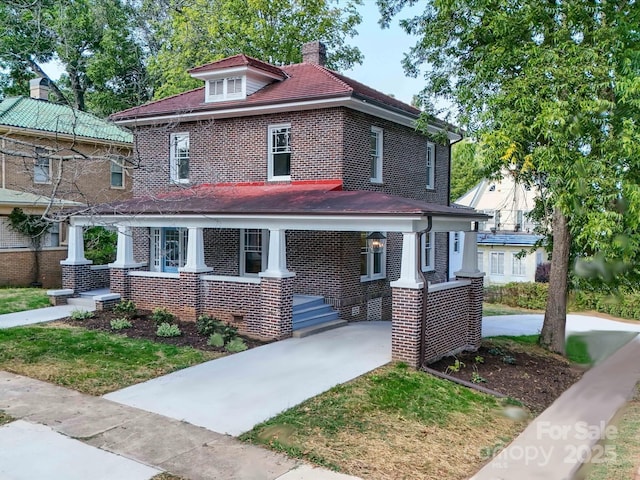 american foursquare style home featuring brick siding, driveway, and a chimney