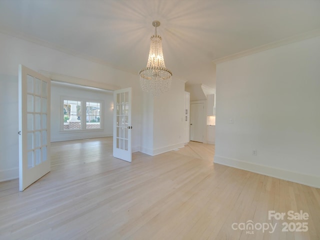 unfurnished dining area with an inviting chandelier, light wood finished floors, french doors, baseboards, and ornamental molding