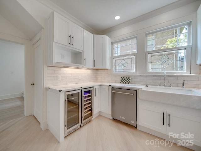 bar featuring plenty of natural light, light wood-style flooring, backsplash, and dishwasher