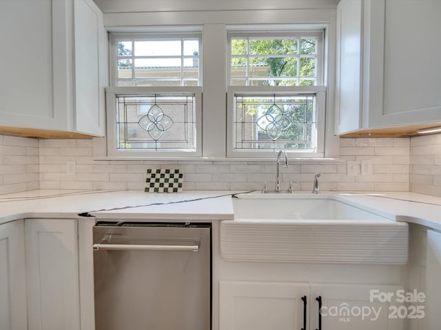 kitchen with stainless steel dishwasher, white cabinets, plenty of natural light, and tasteful backsplash