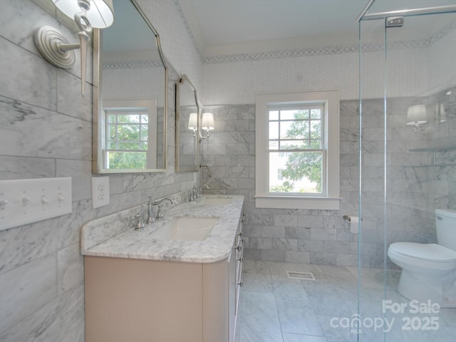 bathroom with double vanity, a sink, toilet, and tile walls