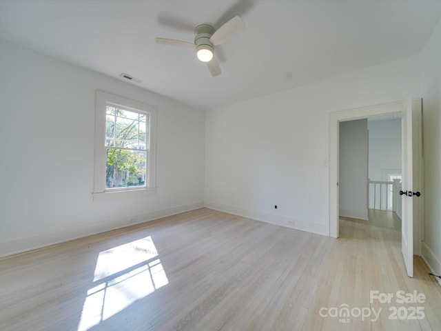 spare room featuring a ceiling fan, baseboards, visible vents, and light wood-type flooring