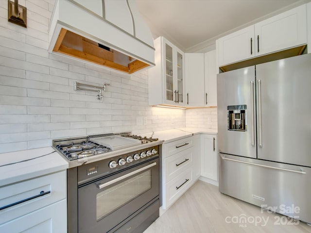 300 W Thomas St, Salisbury, NC 28144 - kitchen with high end appliances, tasteful backsplash, light wood finished floors, glass insert cabinets, and white cabinetry