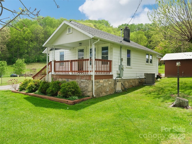 819 Mauney Cove Rd, Waynesville, NC 28786 - rear view of house featuring a shingled roof, central AC, a chimney, covered porch, and a yard
