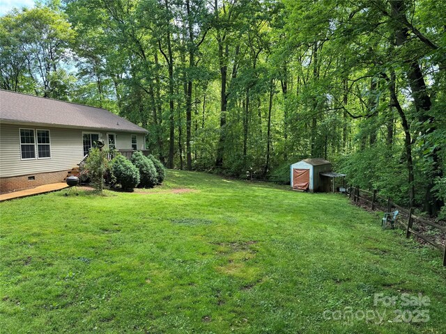 view of yard featuring a storage shed, fence, and an outbuilding