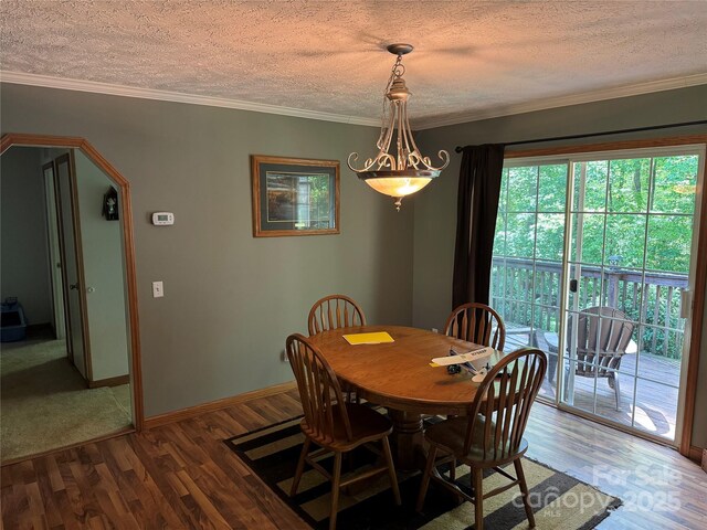 dining space featuring baseboards, arched walkways, a textured ceiling, and wood finished floors