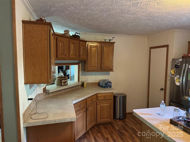 kitchen featuring crown molding, dark wood-style flooring, light countertops, a textured ceiling, and freestanding refrigerator
