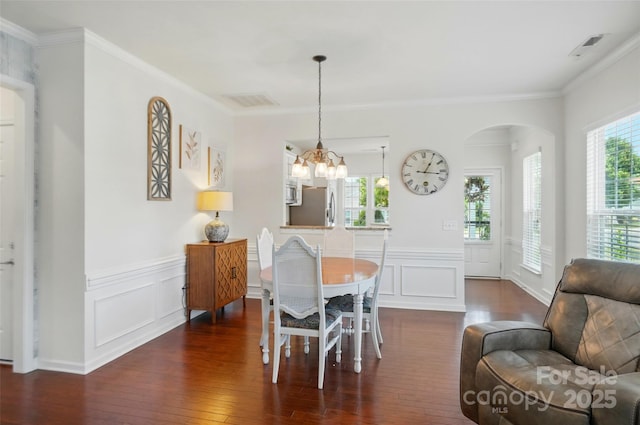 9003 Smokey Hill Ln, Fort Mill, SC 29707 - dining space featuring arched walkways, dark wood finished floors, crown molding, a decorative wall, and a wainscoted wall