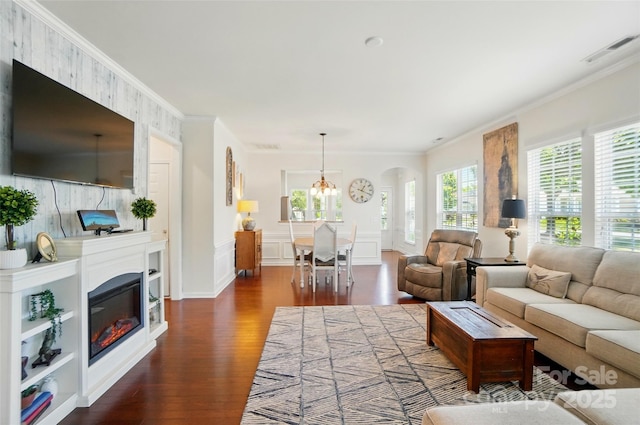 9003 Smokey Hill Ln, Fort Mill, SC 29707 - living area featuring dark wood-style flooring, crown molding, arched walkways, a chandelier, and a glass covered fireplace
