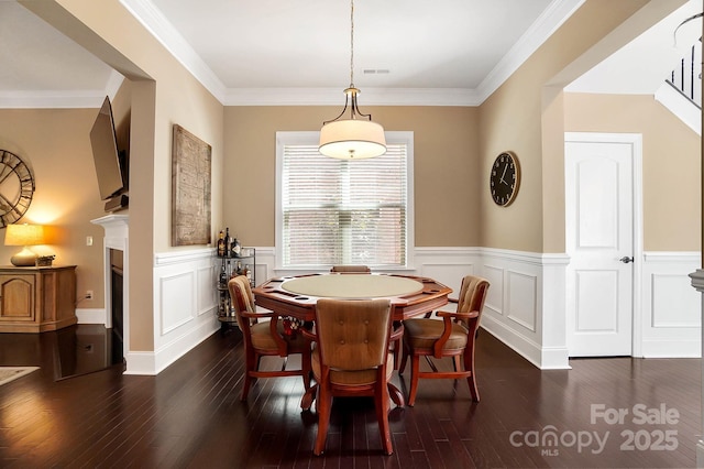 9735 Wheatfield Rd, Charlotte, NC 28277 - dining area featuring dark wood finished floors, a wainscoted wall, a fireplace, a decorative wall, and crown molding