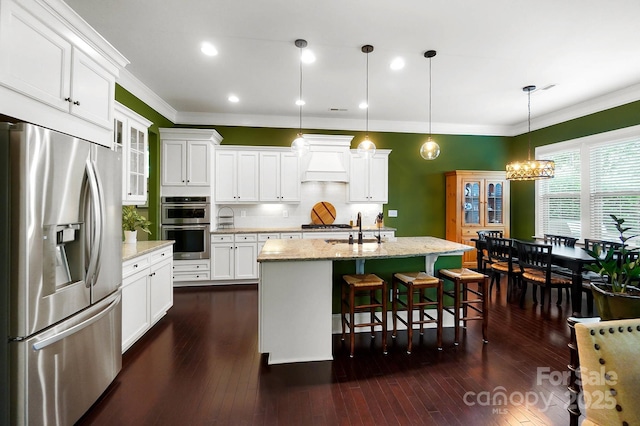 9735 Wheatfield Rd, Charlotte, NC 28277 - kitchen featuring appliances with stainless steel finishes, ornamental molding, a sink, white cabinets, and an island with sink