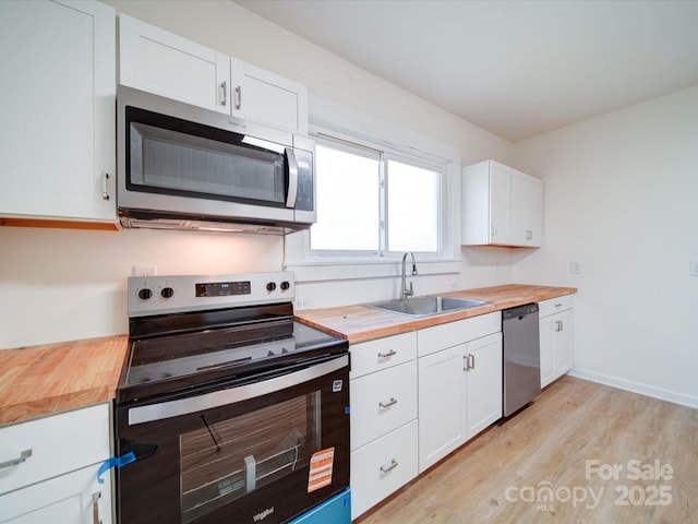 55 Ranlo Ave, Gastonia, NC 28054 - kitchen with butcher block counters, white cabinets, a sink, light wood finished floors, and appliances with stainless steel finishes