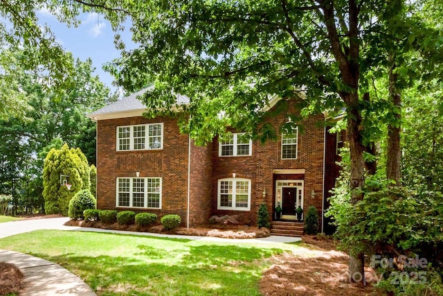 colonial-style house featuring brick siding and a front yard