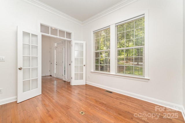 unfurnished room featuring french doors, baseboards, a wealth of natural light, visible vents, and ornamental molding