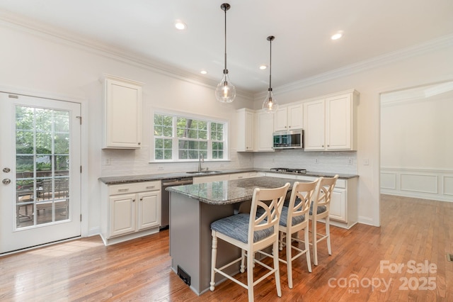 kitchen featuring decorative backsplash, a kitchen island, a kitchen bar, a sink, and stainless steel appliances
