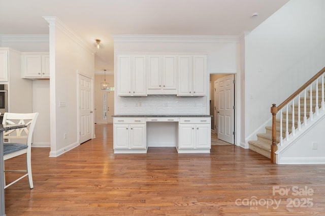 kitchen featuring crown molding, dark countertops, decorative backsplash, and light wood-style floors