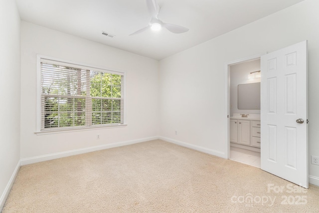 unfurnished bedroom featuring visible vents, baseboards, ensuite bathroom, ceiling fan, and light colored carpet