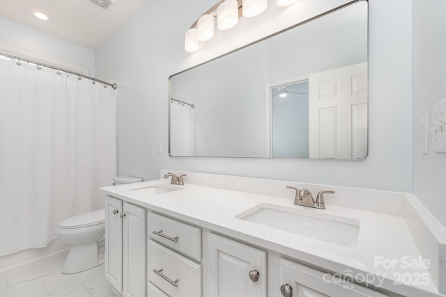 bathroom with double vanity, a sink, marble finish floor, and toilet