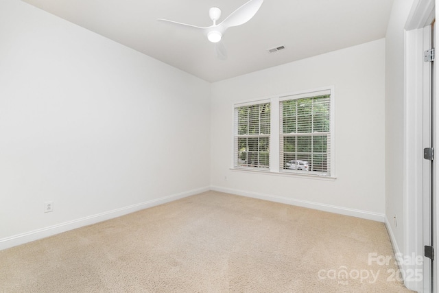 spare room with a ceiling fan, baseboards, visible vents, and light carpet