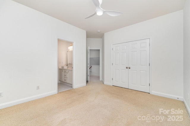 unfurnished bedroom with ceiling fan, light colored carpet, ensuite bath, baseboards, and a closet