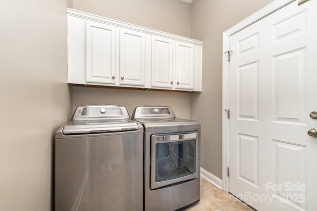washroom featuring light tile patterned floors, cabinet space, and washing machine and clothes dryer