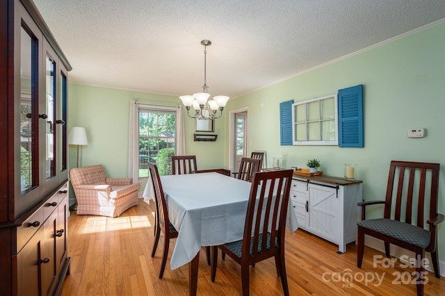 dining area featuring a chandelier, light wood finished floors, crown molding, and a textured ceiling