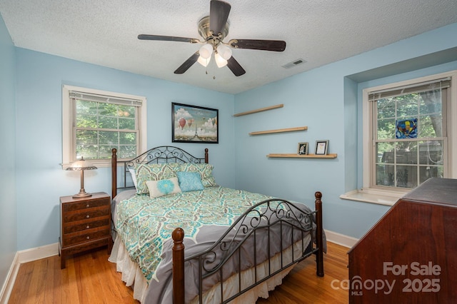 bedroom with wood finished floors, baseboards, a textured ceiling, and ceiling fan