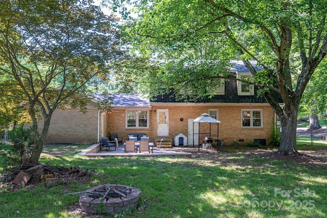 back of house featuring brick siding, a yard, an outdoor living space with a fire pit, and a patio area