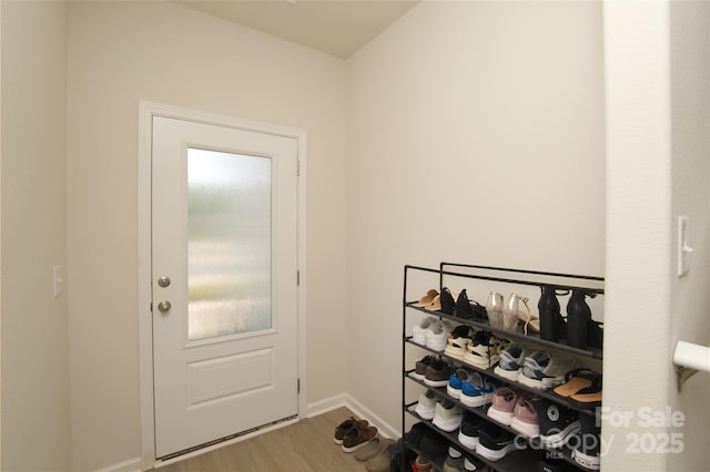 doorway to outside featuring baseboards and wood finished floors