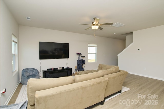 living area featuring visible vents, a ceiling fan, and light wood finished floors