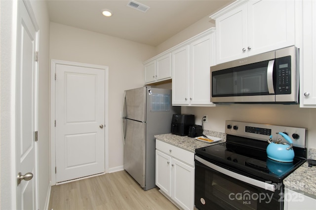 kitchen featuring white cabinets, stainless steel appliances, visible vents, and light wood-type flooring