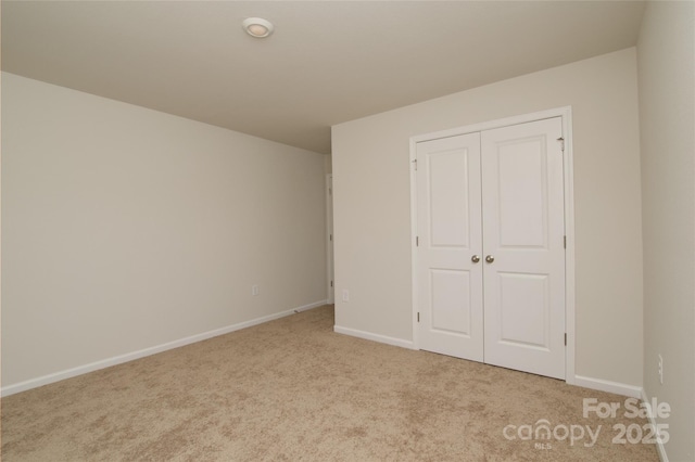 unfurnished bedroom with baseboards, light carpet, and a closet