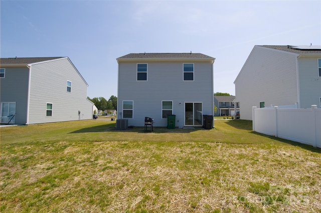 back of house featuring a lawn, fence, and central AC unit