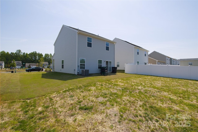 back of property featuring fence, central AC unit, and a lawn