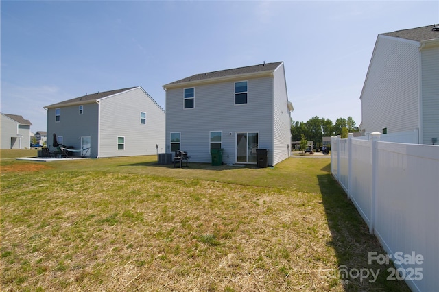 rear view of property with a lawn, fence, and central AC