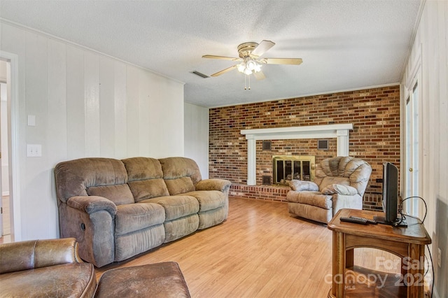 2196 Uphill Ln, Lenoir, NC 28645 - living area featuring ceiling fan, light wood finished floors, brick wall, a textured ceiling, and a brick fireplace